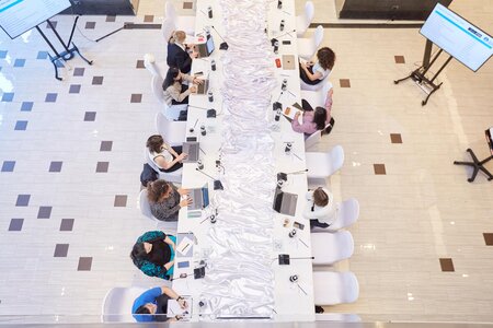 9 people sitting at a long desk with computers